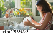 Housewife washing dishes in bright kitchen with window light. Стоковое AI-видео, аниматор Юрий Поздников / Фотобанк Лори