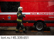 Сотрудник пожарного расчета идет вдоль автомобиля Штаба пожаротушения во время тушения пожара в центре города Москвы, Россия. Редакционное фото, фотограф Николай Винокуров / Фотобанк Лори