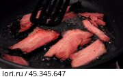 Frying Bacon Slices in a Pan. Crispy Pieces of Delicious Red Thin Smokey Bacon Fried in a Hot Skillet. Traditional Breakfast. Smoked Bacon Rasher or Strip Being Cooked. Grill. Fat High Calorie Food. Стоковое видео, видеограф Марина Демидюк / Фотобанк Лори