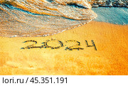 Морская волна смывает с песчаного берега надпись "2024" Стоковое фото, фотограф Оксана / Фотобанк Лори