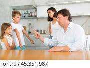 At home in kitchen, outraged mom and dad scold their son and daughter for disobedience. Стоковое фото, фотограф Яков Филимонов / Фотобанк Лори