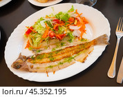 There is plate with fried solea flatfish and salad of fresh veg on wooden table. Стоковое фото, фотограф Яков Филимонов / Фотобанк Лори
