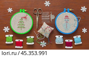 Winter needlework. Video of cross stitch Christmas tree and snowman in hoop and embroidery accessories on wooden background. Handmade gifts and DIY concept. Flat lay, close-up, top view. Стоковое видео, видеограф Виктория Катьянова / Фотобанк Лори