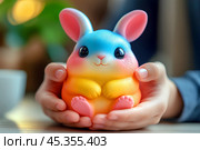 Яркая разноцветная игрушка в ладонях. Стоковое AI-изображение, AI-художник Щеголева Ольга / Фотобанк Лори