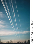 Chemtrail conspiracy theory. Long-lasting condensation trails left in sky by high-flying aircraft are actually chemtrails consisting of chemical or biological agents, sprayed for nefarious purposes. Стоковое AI-изображение, AI-художник Юлия Петровская / Фотобанк Лори