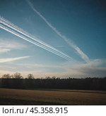 Chemtrail conspiracy theory. Long-lasting condensation trails left in sky by high-flying aircraft are actually chemtrails consisting of chemical or biological agents, sprayed for nefarious purposes. Стоковое AI-изображение, AI-художник Юлия Петровская / Фотобанк Лори
