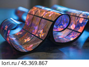 Flexible oled display showing flower pattern bending on a table. Стоковое AI-изображение, AI-художник Иван Рябоконь / Фотобанк Лори