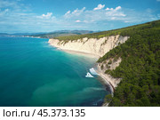 Panoramic view of the wild narrow beach “Blue Abyss” under a steep white cliff overgrown with mountain pines with amazing turquoise water and surf wave near the shore. Aerial photography. Стоковое фото, фотограф Роман Дзюбало / Фотобанк Лори