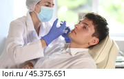 Young male patient lying on clinical chair undergoing face care procedure by injection method. Стоковое видео, видеограф Яков Филимонов / Фотобанк Лори