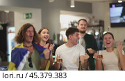 Company of excited sports fans waving flag of Sweden and supporting national team with beer in bar. Стоковое видео, видеограф Яков Филимонов / Фотобанк Лори