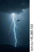 The aircraft encounters a severe thunderstorm, surrounded by dark clouds and illuminated by bright lightning strikes, highlighting the danger in the sky. Causes of air crashes. Generative AI. Стоковое AI-изображение, AI-художник Юлия Петровская / Фотобанк Лори