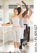 Asian woman mastering third position at group ballet rehearsal. Стоковое фото, фотограф Яков Филимонов / Фотобанк Лори