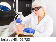 Female beautician making laser resurfacing of aged female client. Стоковое фото, фотограф Яков Филимонов / Фотобанк Лори