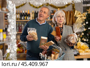 Elderly spouses choose consider nougat, panettone, marzipan, cookies, chocolate. Стоковое фото, фотограф Яков Филимонов / Фотобанк Лори