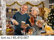 Elderly couple choose from several deserts, consider nougat, panellets, marzipan. Стоковое фото, фотограф Яков Филимонов / Фотобанк Лори