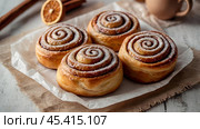 The cinnabons. Close-up of cinnamon buns. Beautiful buns with fresh cinnamon and icing on a wooden table. Fragrant homemade New Year's pastries. Стоковое AI-изображение, AI-художник Photojuli / Фотобанк Лори