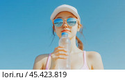Летняя гидратация: молодая женщина освежается водой на пляже. Стоковое AI-изображение, AI-художник ФотоИнтеллект / Фотобанк Лори