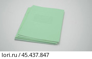 A pack of green school notebooks fall from above on a white table, isolates on a white background. Стоковое видео, видеограф Дмитрий Нечаев / Фотобанк Лори