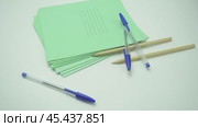 Pens and pencils fall from above on a pack of green school notebooks, isolates on a white background. Стоковое видео, видеограф Дмитрий Нечаев / Фотобанк Лори