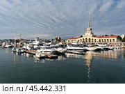 Yachts and boats docked at a marina next to a historic building in a coastal city under a cloudy sky in the late afternoon - Sochi, Russia April 14, 2023. Редакционное фото, фотограф Наталия Попова / Фотобанк Лори