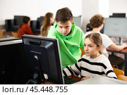 Preteen schoolboy helping girl classmate during informatics lesson. Стоковое фото, фотограф Яков Филимонов / Фотобанк Лори