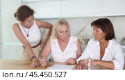 Three women help each other sort out financial documents in the kitchen of a home. Стоковое видео, видеограф Яков Филимонов / Фотобанк Лори