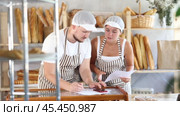 Man and woman sellers in bakery make calculations, work with paper documents and count using phone. Стоковое видео, видеограф Яков Филимонов / Фотобанк Лори