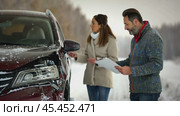 Two individuals assess a car accident in a snowy environment, with a man holding a clipboard next to a damaged car. The scene underscores the importance of car insurance during winter. Стоковое AI-видео, аниматор Igor Tichonow / Фотобанк Лори