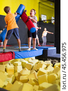 Preteen girl fighting by pugil stick with boy on inflatable beam. Стоковое фото, фотограф Яков Филимонов / Фотобанк Лори
