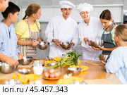 During cooking lesson, male cook tells children about culinary rules, woman assistant helps child. Стоковое фото, фотограф Яков Филимонов / Фотобанк Лори