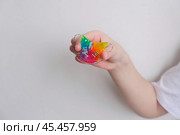 Детская зубная пластина радужного цвета. Ребенок держит в руках ортодонтическую пластинку, чтобы выровнять зубы и расширить челюсть. Стоковое фото, фотограф Терехова Марина / Фотобанк Лори