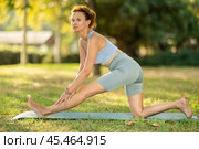 Woman practicing yoga in garden, performing Anjaneyasana, or Crescent Moon Pose. Стоковое фото, фотограф Яков Филимонов / Фотобанк Лори