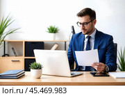 A businessman works in an office with a laptop. Стоковое AI-изображение, AI-художник RamA / Фотобанк Лори