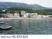 Sutomore, Montenegro 07.21.24 Boats and a shore with vacationers, sunbathers and swimmers. Hotels, sun umbrellas, Adriatic waves, buoys. Beach tourism. Vacation travel. Summer day. Pebble rock beach. Редакционное фото, фотограф Юлия Петровская / Фотобанк Лори