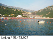 Canj, Montenegro 07.20.2024 Boats and a shore with vacationers, sunbathers and swimmers. Hotels, sun umbrellas, Adriatic waves, buoys. Beach tourism. Vacation travel. Summer day. Pebble rock beach. Редакционное фото, фотограф Юлия Петровская / Фотобанк Лори