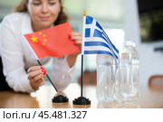 Unrecognizable girl sets midget flags of Greece and China before international negotiations. Стоковое фото, фотограф Яков Филимонов / Фотобанк Лори