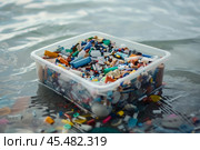 Container full of microplastics floating on polluted water surface. Стоковое AI-изображение, AI-художник Иван Рябоконь / Фотобанк Лори