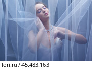Portrait of a young female covered with veil. Woman is dressed in a peignoir and wears a necklace and earrings. Стоковое фото, фотограф Сергей Пристяжнюк (Serg Zastavkin) / Фотобанк Лори