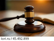 A judge's hammer with a wooden stand and an open book in the background. Стоковое AI-изображение, AI-художник RamA / Фотобанк Лори
