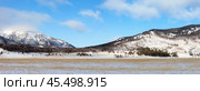 Panoramic view of Goloustnaya River valley framed by snow-capped mountains on sunny January day. Coast of Baikal Lake. Pribaikalsky National Park. Beautiful winter landscape. Natural background. Стоковое фото, фотограф Виктория Катьянова / Фотобанк Лори