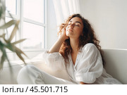 Sweet idleness. Lazy young hispanic lady sit in relaxed pose on big comfy sofa at living room interior breath air dream imagine. Successful female new flat apartment buyer rest at home feel pleasure. Стоковое AI-изображение, AI-художник Sergey Grishin / Фотобанк Лори