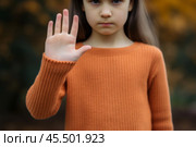 Close-up of a young girl showing a hand gesture to protest against domestic violence and discrimination in a peaceful stand. Стоковое AI-изображение, AI-художник Sergey Grishin / Фотобанк Лори