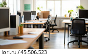 Light wood desks and black ergonomic chairs fill a bright, modern office. Стоковое AI-изображение, AI-художник Сергей Толмачёв / Фотобанк Лори