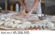 Hands of skilled female baker in striped apron rolling out soft dough on flour-dusted wooden table in bakery. Cropped shot. Стоковое видео, видеограф Яков Филимонов / Фотобанк Лори