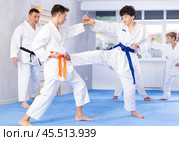 Teenagers in kimonos working on kicks in pairs during group training. Стоковое фото, фотограф Яков Филимонов / Фотобанк Лори
