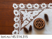 Beautiful white handmade tablecloth with lace patterns embroidered in richelieu style or cutwork embroidery and old wooden box on wooden table. Retro still life. Vintage handicraft for home decoration. Стоковое фото, фотограф Виктория Катьянова / Фотобанк Лори