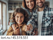 Homeowners. Happy young Caucasian family spouses standing indoors holding car house flat apartment keys, celebrating new purchase buying real estate. Mortgage loan. New home. Mother, father and child. Стоковое AI-изображение, AI-художник Марина Демидюк / Фотобанк Лори