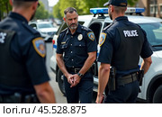 Uniformed police officers on duty outdoors, law enforcement professionals near patrol car in urban setting, public safety officials maintaining order on city streets. Стоковое AI-изображение, AI-художник Павел Муравьев / Фотобанк Лори