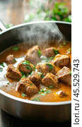 Steaming beef stew with herbs simmering in pan. Стоковое AI-изображение, AI-художник Юрий Поздников / Фотобанк Лори