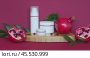 Video of natural cosmetic moisturizers for face and hands: cream, mousse, lotion with vitamin extract of pomegranate on wooden podium on burgundy background. Use of vitamin fruit extracts in cosmetics. Стоковое видео, видеограф Виктория Катьянова / Фотобанк Лори